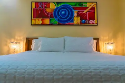 a bedroom with a white bed with a painting on the wall at Hotel Casa La Tablada Manga in Cartagena de Indias