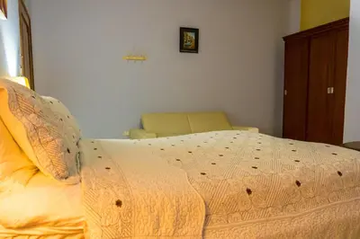 a bedroom with a large bed and a chair at Hotel Casa La Tablada Manga in Cartagena de Indias
