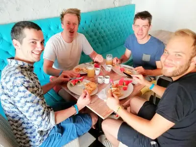 a group of men sitting around a table eating food at Hostel la Antigua Capsula in Cartagena de Indias