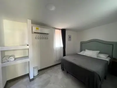 a small bedroom with a bed and a refrigerator at Hostel la Antigua Capsula in Cartagena de Indias