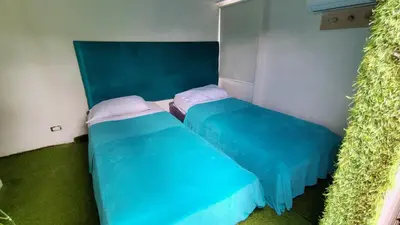 two beds in a small room with blue sheets at Hostel la Antigua Capsula in Cartagena de Indias