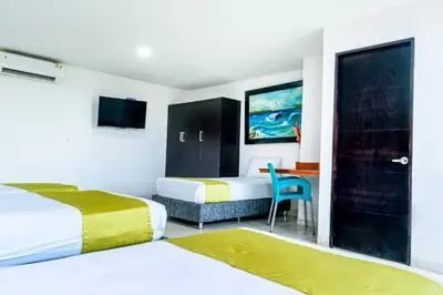 a bedroom with two beds and a desk with a chair at Hotel Caribe Plaza Barranquilla in Barranquilla