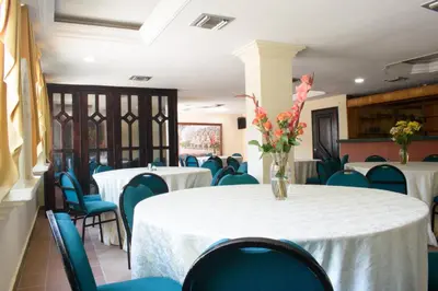 a room with tables and chairs and a vase of flowers at Hotel Caribe Plaza Barranquilla in Barranquilla