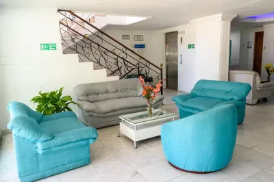 a living room with blue chairs and a staircase at Hotel Caribe Plaza Barranquilla in Barranquilla