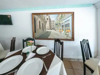 a dining room with a table and a painting on the wall at Hotel Caribe Plaza Barranquilla in Barranquilla