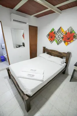 a bedroom with a bed with white sheets at Hotel La Casona de Getsemani in Cartagena de Indias