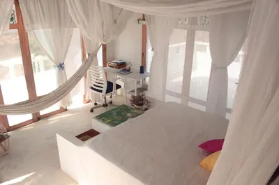 a bedroom with white curtains and a bed with a desk at Frente al Mar in Santa Veronica