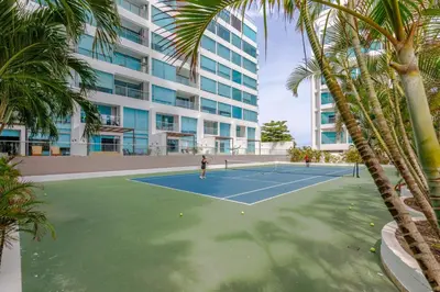 a person playing tennis on a tennis court in front of a building at Escapada 5 estrellas frente al mar - sonest morros in Cartagena de Indias