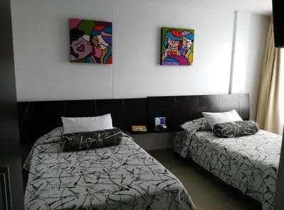 two beds in a room with paintings on the wall at Hotel Altamar Cartagena in Cartagena de Indias