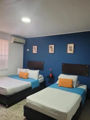two beds in a room with a blue wall at Costana - Hostal in Cartagena de Indias