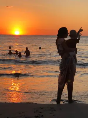 a woman holding a child on the beach at sunset at Casa Miramar in Santa Marta