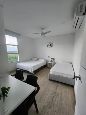 a bedroom with two beds and a table and chairs at cabaña puerto velero in Puerto Caimán