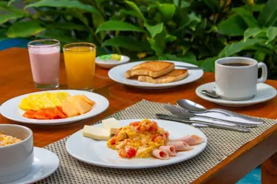 a table with plates of breakfast food and cups of coffee at Hotel Playa Club in Cartagena de Indias