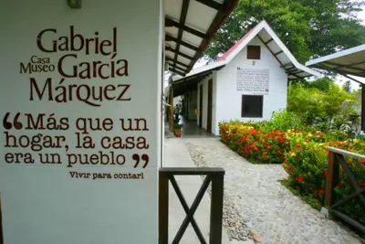 a sign in front of a white building with flowers at Casa Turística Realismo Mágico in Aracataca