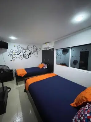 a bedroom with two beds and a mirror at Casa Turística Realismo Mágico in Aracataca
