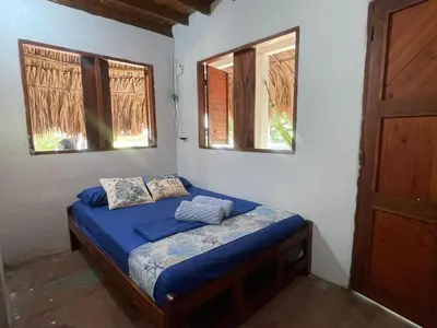 a bedroom with a bed with blue sheets and two windows at Luna azul in San Bernardo del Viento