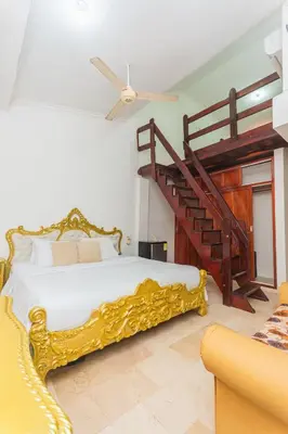a bedroom with a gold bed and a staircase at Hotel Baluarte Cartagena Boutique in Cartagena de Indias