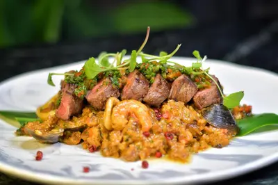 a plate of food with sausage and risotto at Hotel Baluarte Cartagena Boutique in Cartagena de Indias