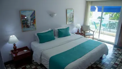 a bedroom with a large bed with blue pillows at Hotel Bahia Cartagena in Cartagena de Indias
