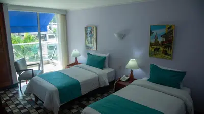a hotel room with two beds and a window at Hotel Bahia Cartagena in Cartagena de Indias