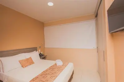 a bedroom with a white bed and a large window at Hotel Aixo Suites By GEH Suites in Cartagena de Indias