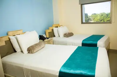 two beds in a room with a window at Hotel Med Barranquilla Centro in Barranquilla