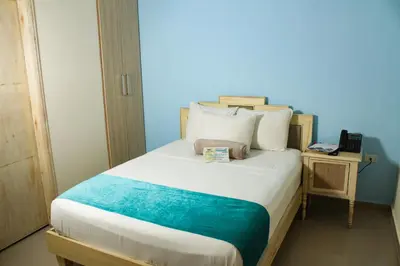 a bedroom with a bed with a blue wall at Hotel Med Barranquilla Centro in Barranquilla