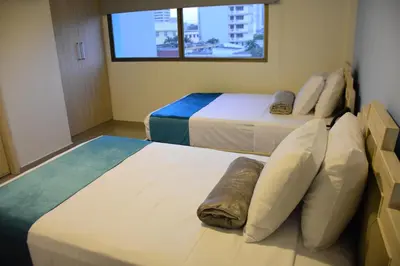 two beds in a hotel room with a window at Hotel Med Barranquilla Centro in Barranquilla