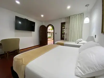a bedroom with two beds and a flat screen tv at Hotel Casa Colonial in Barranquilla