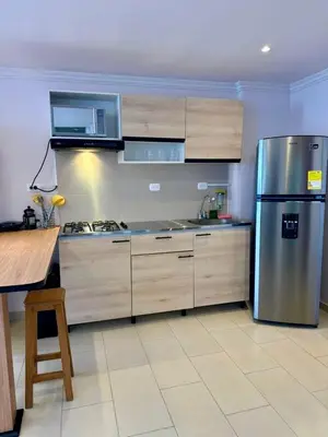 a kitchen with a stainless steel refrigerator and wooden cabinets at Apartamentos Cartagena Colonial in Cartagena de Indias