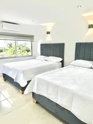 two beds in a white bedroom with a window at Hotel Boutique Casa Berastegui in Puerto Colombia