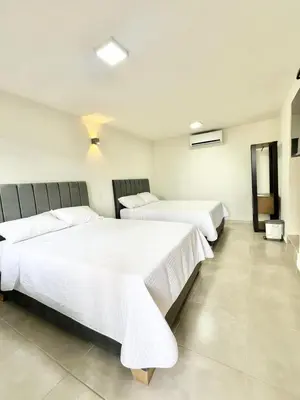a room with three beds with white sheets at Hotel Boutique Casa Berastegui in Puerto Colombia