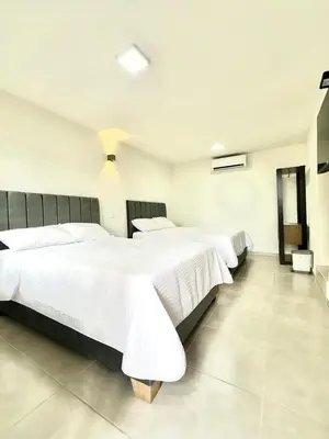 two beds in a hotel room with white sheets at Hotel Boutique Casa Berastegui in Puerto Colombia