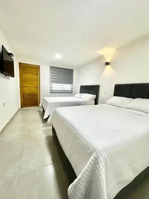 a bedroom with two beds and a television on the wall at Hotel Boutique Casa Berastegui in Puerto Colombia