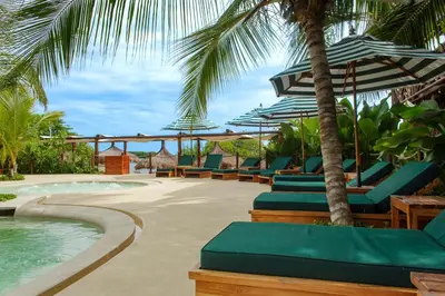 a row of lounge chairs with umbrellas and a swimming pool at Aura Hotel Barú in Baru