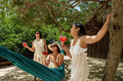 a group of women sitting in a hammock with wine glasses at Aura Hotel Barú in Baru