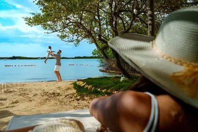 a man sitting on the beach with a man holding a child at Aura Hotel Barú in Baru