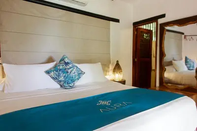 a bed with blue and white pillows on it at Aura Hotel Barú in Baru