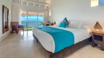 a bedroom with a large bed with a view of the ocean at Aura Hotel Barú in Baru