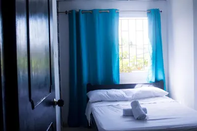 a bedroom with a bed with blue curtains and a window at Hotel Paseo Bolivar in Cartagena de Indias