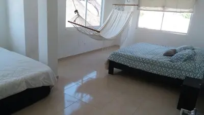 a bedroom with a hammock and a bed and a window at Blue Gold Beach in Juan de Acosta