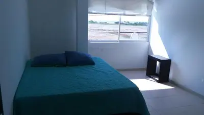 a bedroom with a bed with a green comforter and a window at Blue Gold Beach in Juan de Acosta