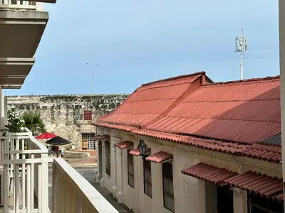 a building with red roofs with a castle in the background at Apartamento Alvarez in Cartagena de Indias
