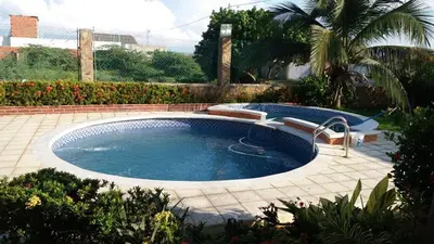 a large swimming pool with a fountain in a yard at Cabaña Villa Flower Gold in Juan de Acosta