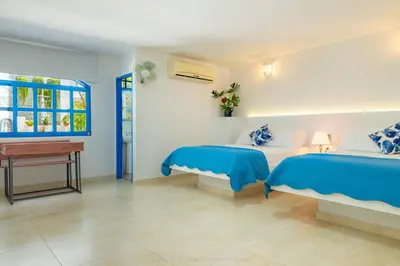 a bedroom with two beds and a desk and a window at Casa Caribe Colonial in Barranquilla