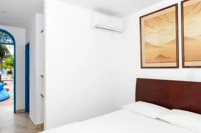 a bedroom with white walls and a bed with a wooden headboard at Casa Caribe Colonial in Barranquilla