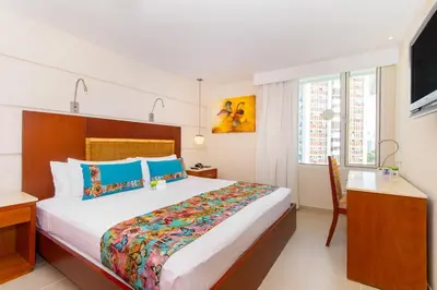 a bedroom with a bed and a desk and a television at Hotel Dann Cartagena in Cartagena de Indias