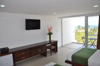 a bedroom with a bed and a desk and a window at Hotel Isla Verde in Tubará