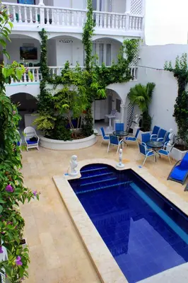 a courtyard with a pool and chairs and a building at Hotel Casa Mara By Akel Hotels in Cartagena de Indias