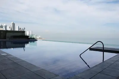 a swimming pool with a bench next to the water at Apartamento Encantador - H2 Condominio in Cartagena de Indias